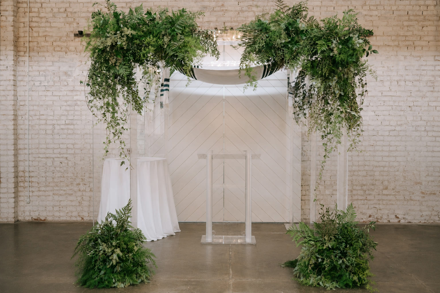 The clear acrylic chuppah dressed with greenery
