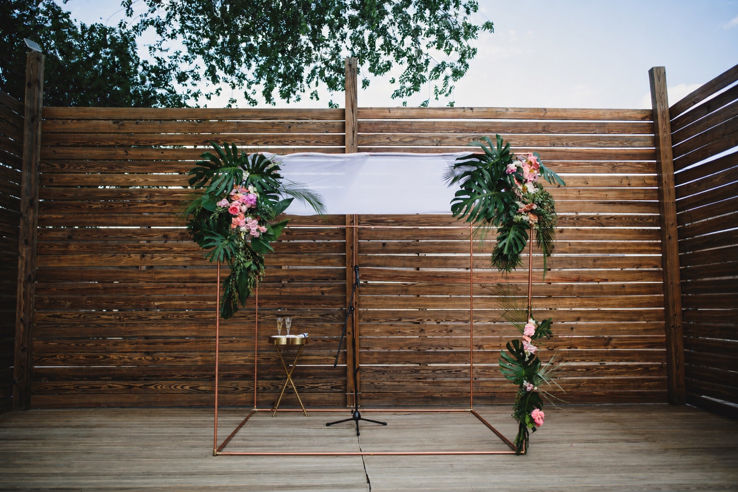 The copper chuppah outdoors on a patio under open sky